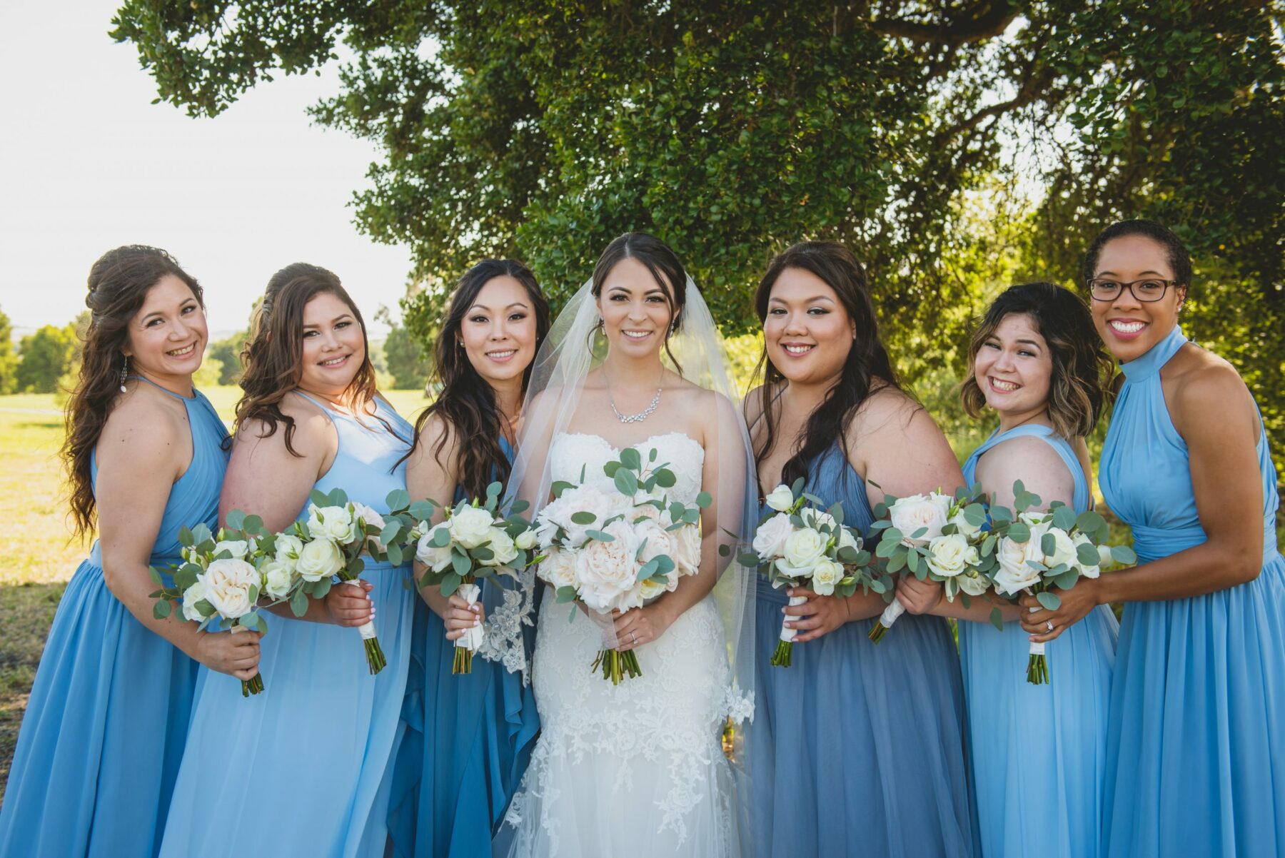 Bride in classic ball gown wedding dress poses with bridesmaids, wearing  chocolate brown strapless d